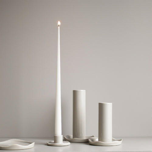 Set of three white candle holders with a lit candle on a gray background