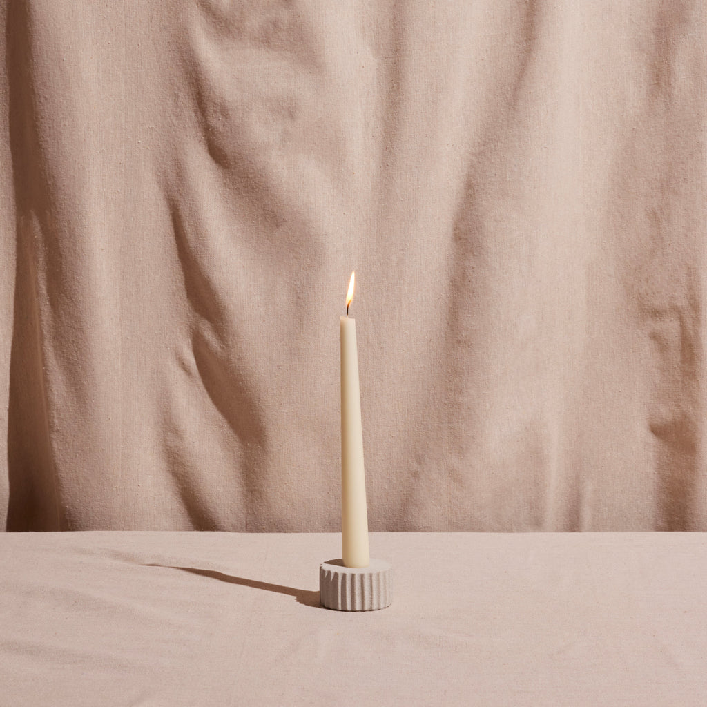 Alt Text: Minimalist fluted stone candle holder with ivory taper candle in a soft neutral palette and timeless European-inspired styling | Sorelle Rossi Shoppe