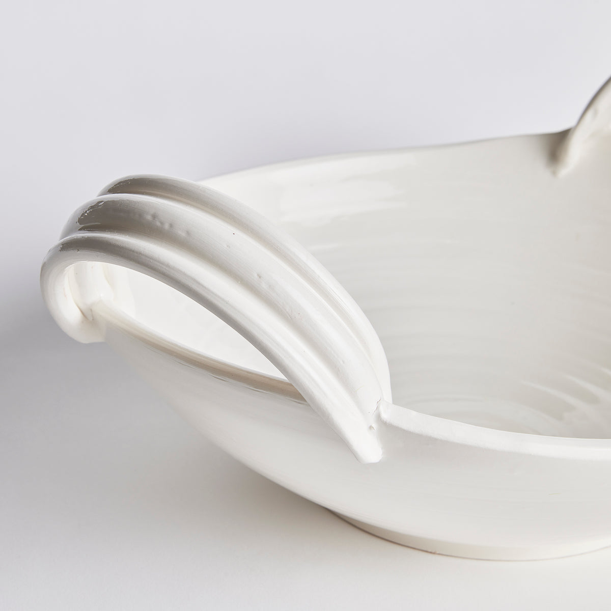Close-up of a white ceramic pitcher with a silver handle on a light gray background