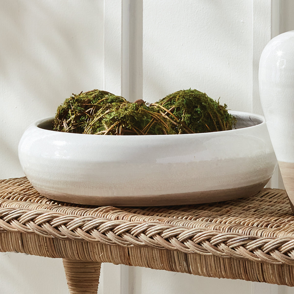 White ceramic bowl with moss on a woven surface