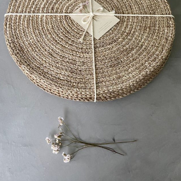 Handwoven round placemats in a soft natural beige tone featuring tightly braided woven texture and an organic neutral finish. Artisan-inspired woven table placemats styled with twine wrapping, perfect for European-inspired dining tables, layered tabletop decor, and timeless everyday entertaining | Sorelle Rossi Shoppe