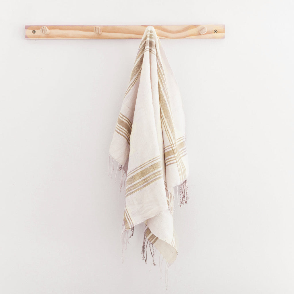 Soft beige linen tea towels hanging on brass hooks in a warm neutral kitchen setting | Sorelle Rossi Shoppe
