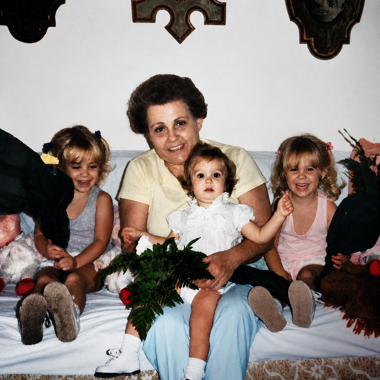 Woman sitting on a couch with three children, holding a bouquet of flowers, in a vintage setting.