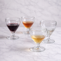 Elegant cocktail glasses with colored stems displayed on a neutral linen tablecloth for entertaining and tablescape styling.