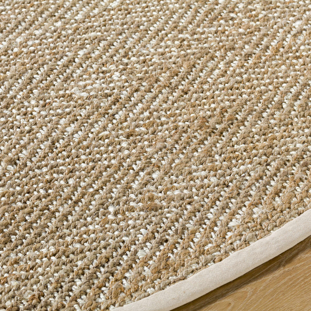 Close-up of a textured beige and white carpet bordering a wooden floor.
