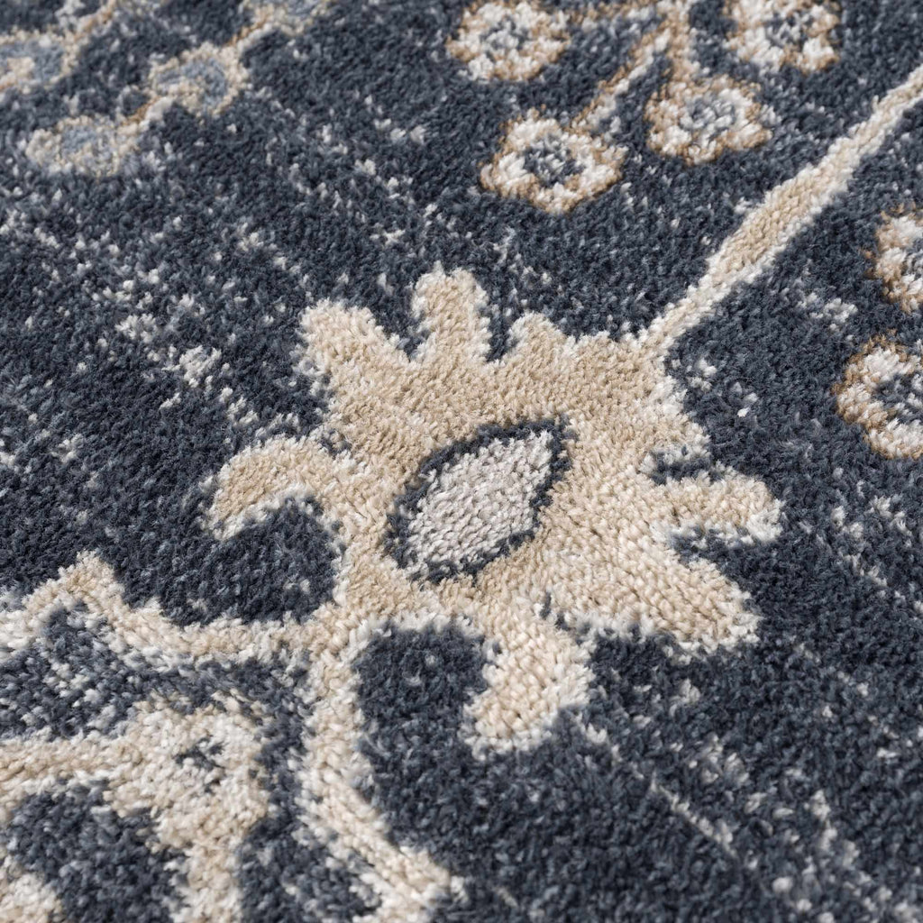 Close-up of a textured rug with floral patterns in beige and gray.