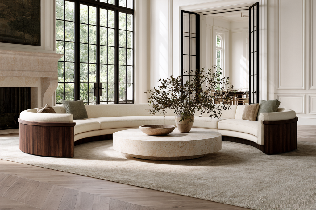 A luxury curved modular sofa in cream and dark wood sits in a grand, bright living room with a stone coffee table, a large window, and a fireplace.
