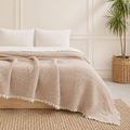 Taupe knit blanket with soft woven texture and fringe detailing, styled in a cozy neutral bedroom with timeless layered European-inspired decor. | Sorelle Rossi Shoppe