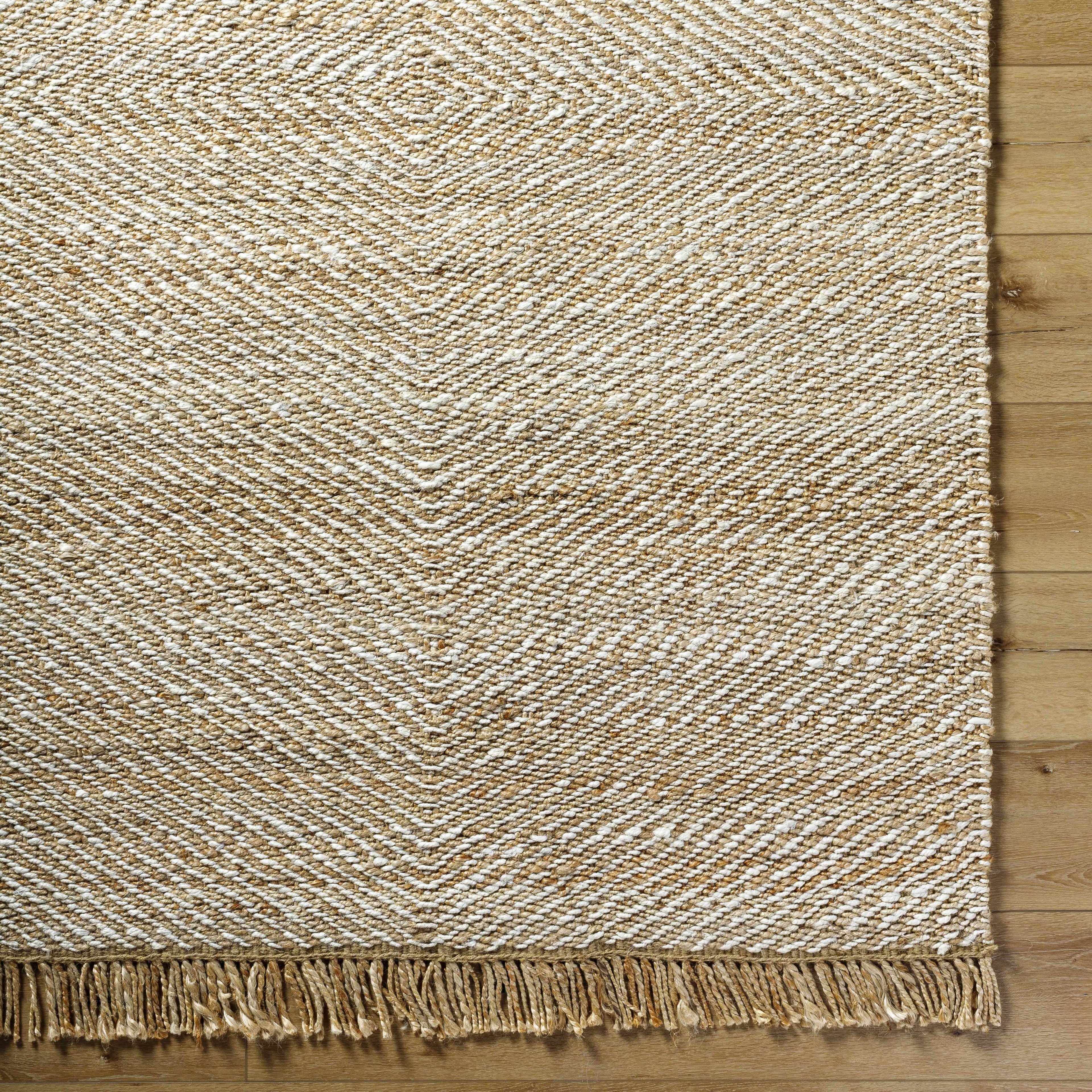 Textured beige rug with fringes on a wooden floor