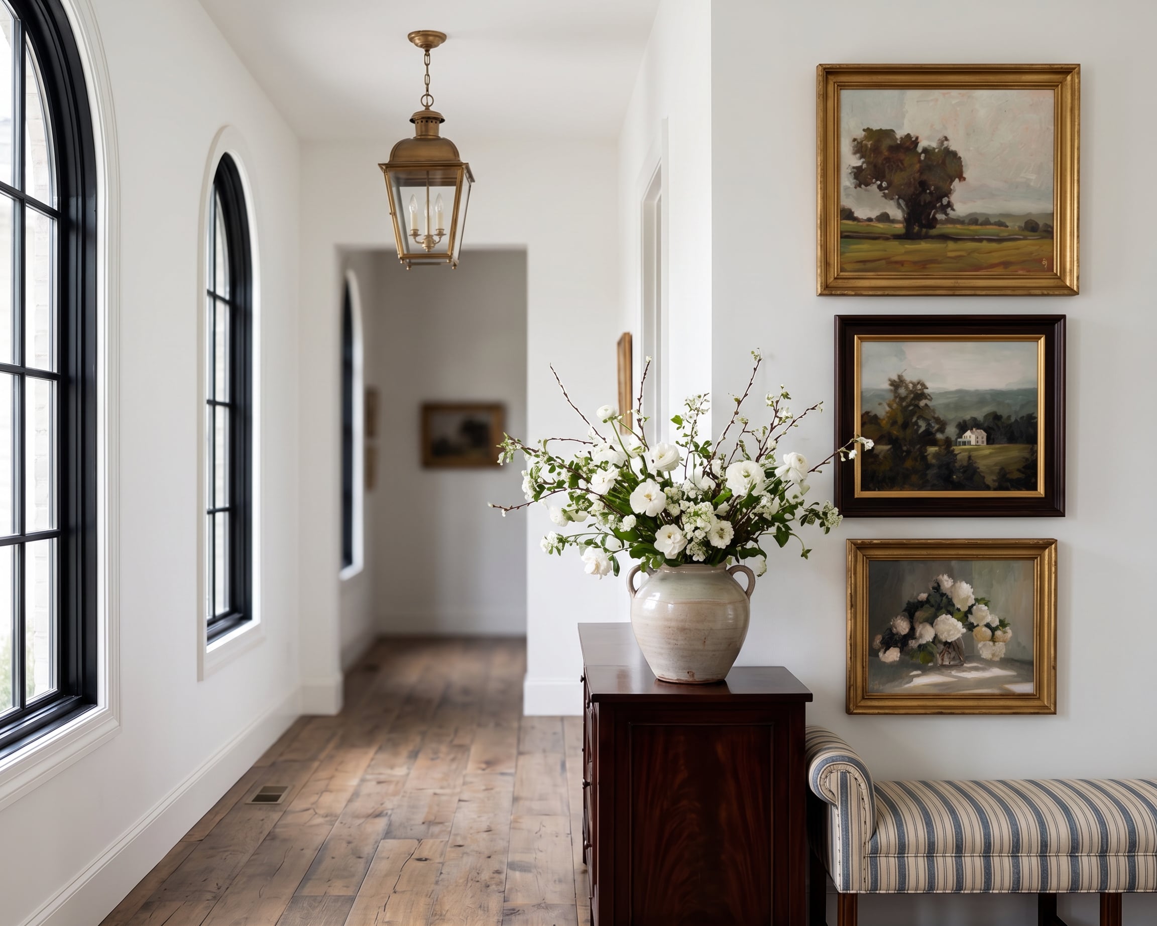 Elegant interior hallway with framed artworks and a vase of flowers.