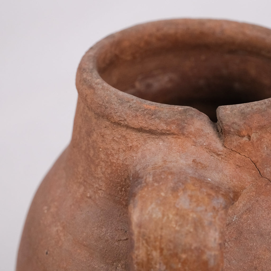 Close-up of a brown ceramic pot with a handle on a white background