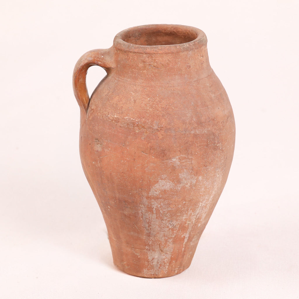 Terracotta jar with a single handle on a white background