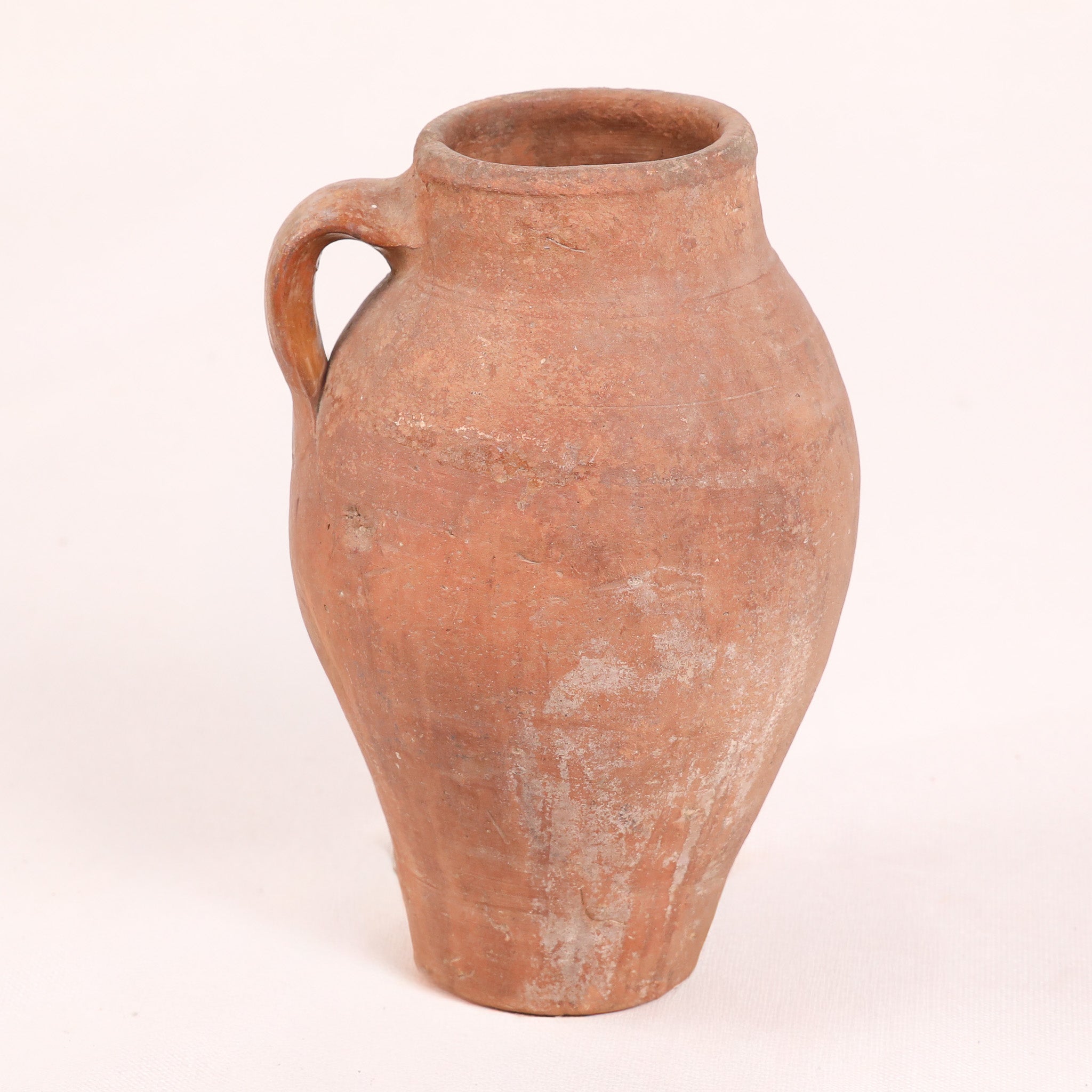 Terracotta jar with a single handle on a white background