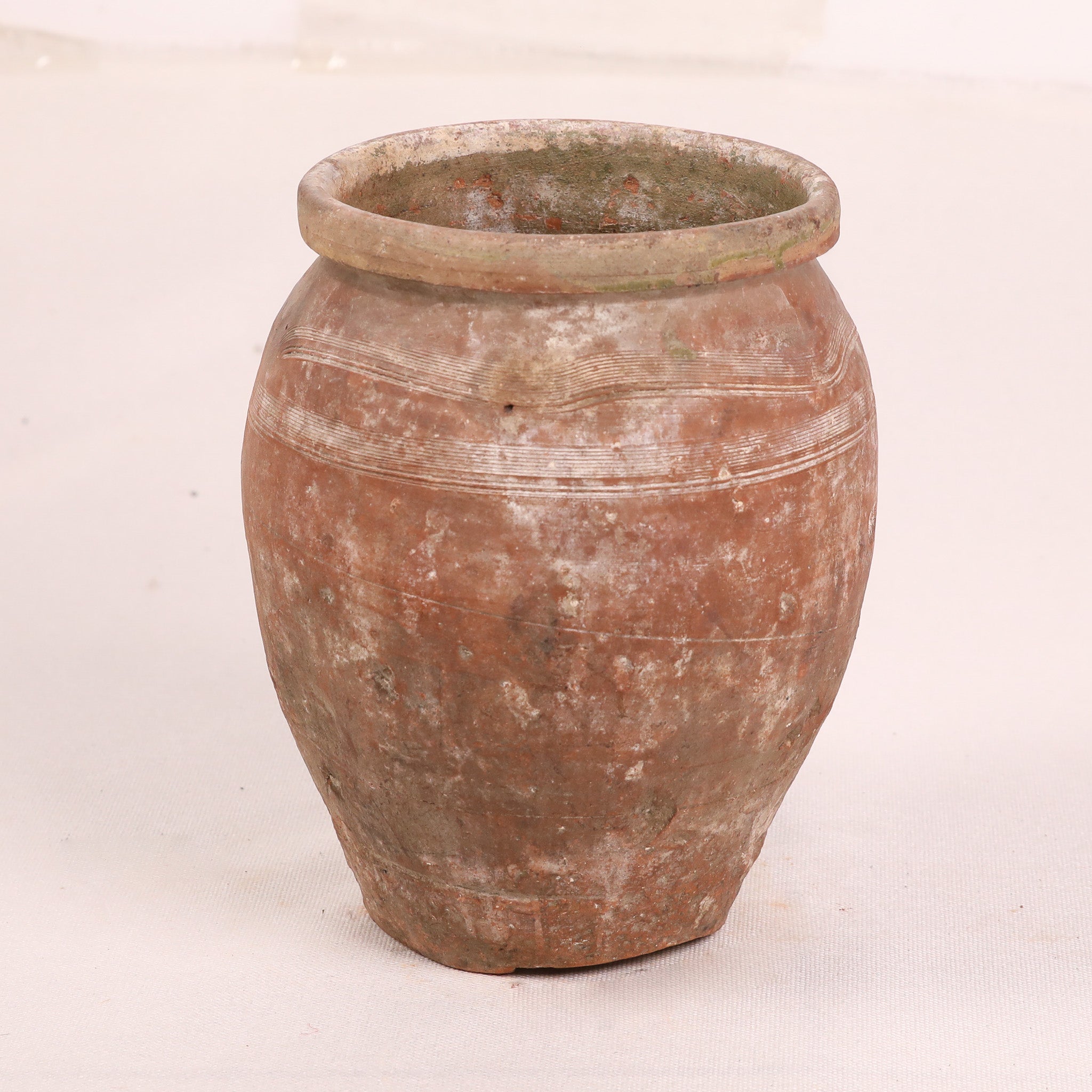 Terracotta jar with a textured surface on a white background