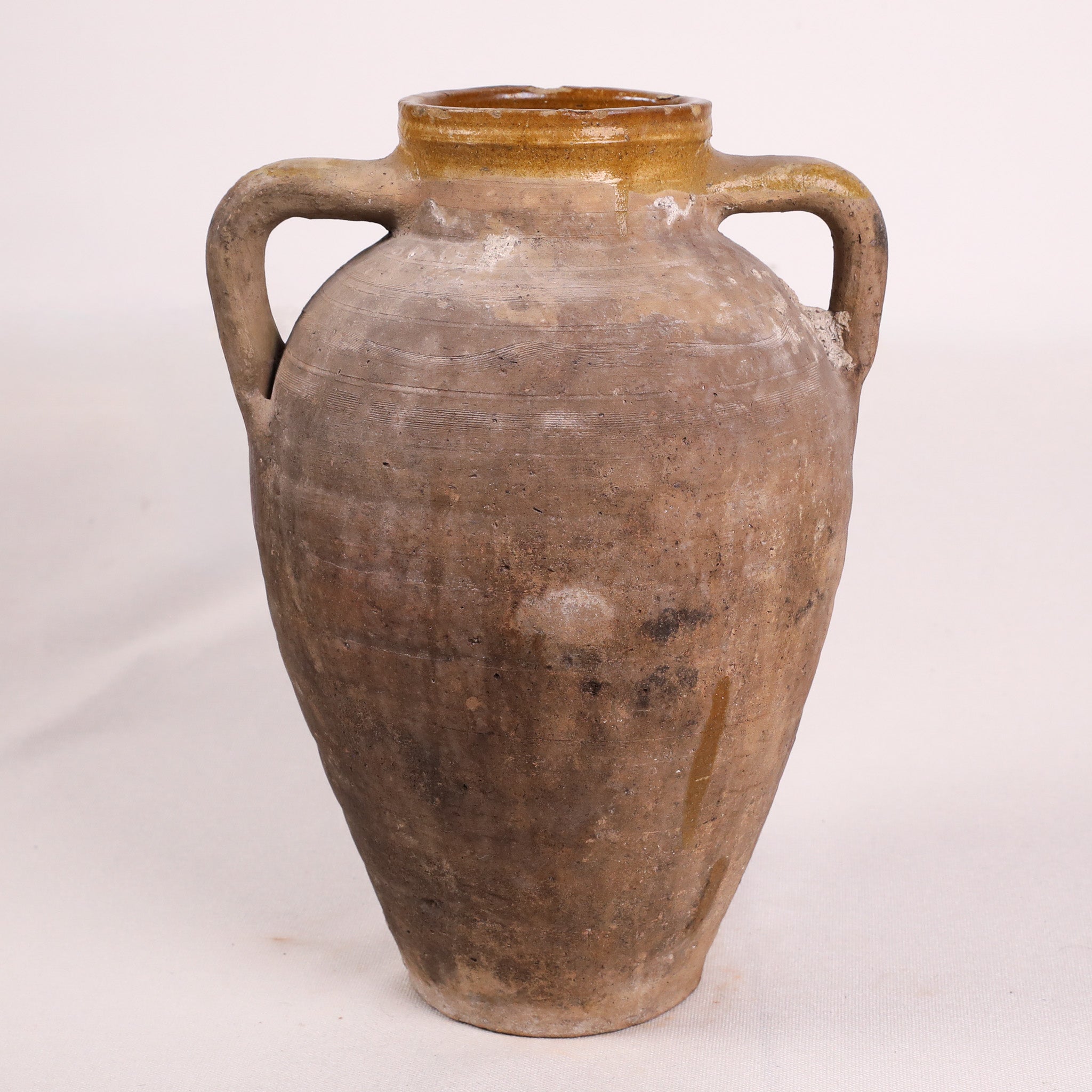 Brown ceramic jar with handles on a white background