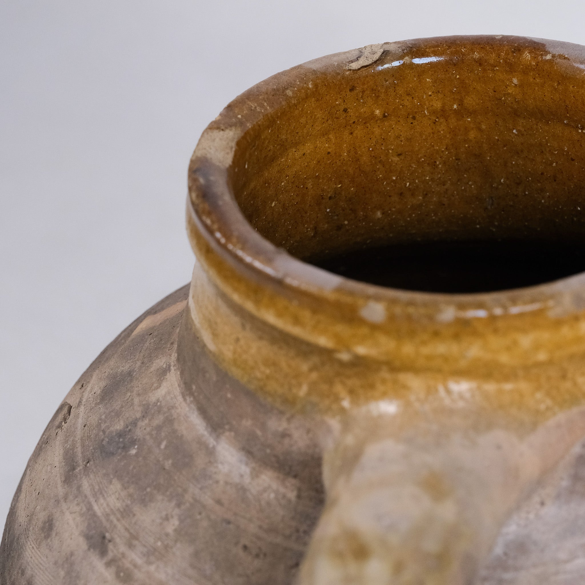 Close-up of a ceramic jar with a brown glaze on a gray background