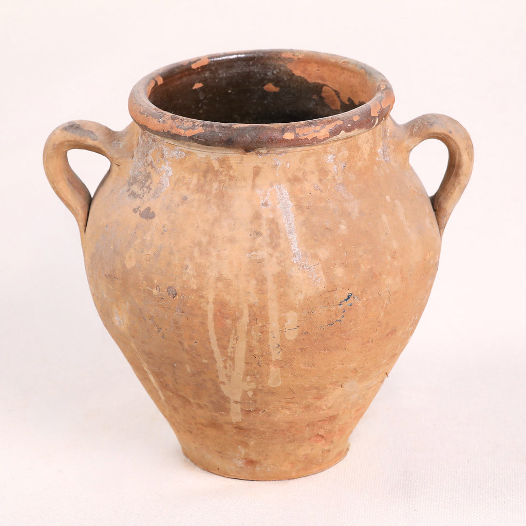 Ancient terracotta jar with two handles on a white background