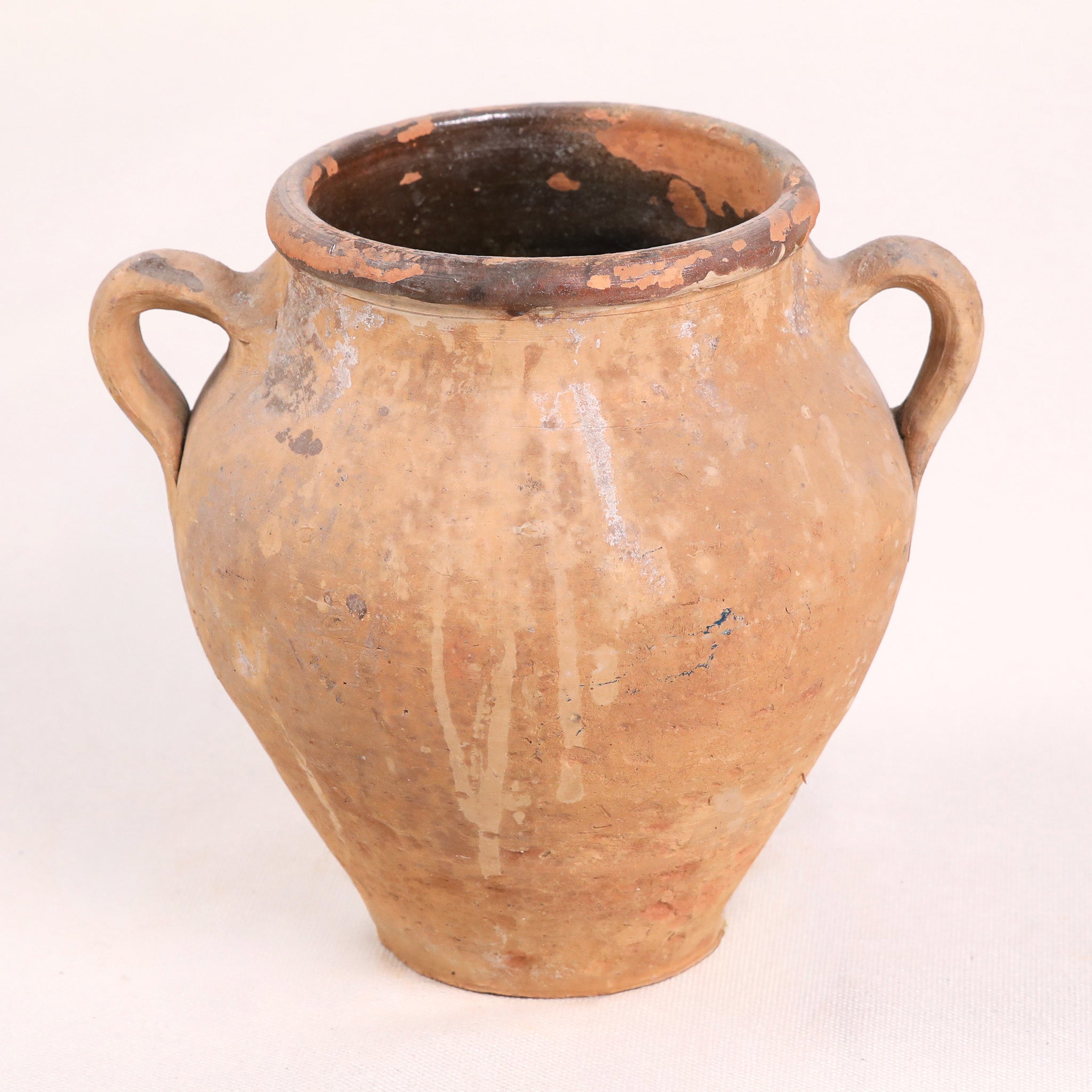 Ancient terracotta jar with two handles on a white background