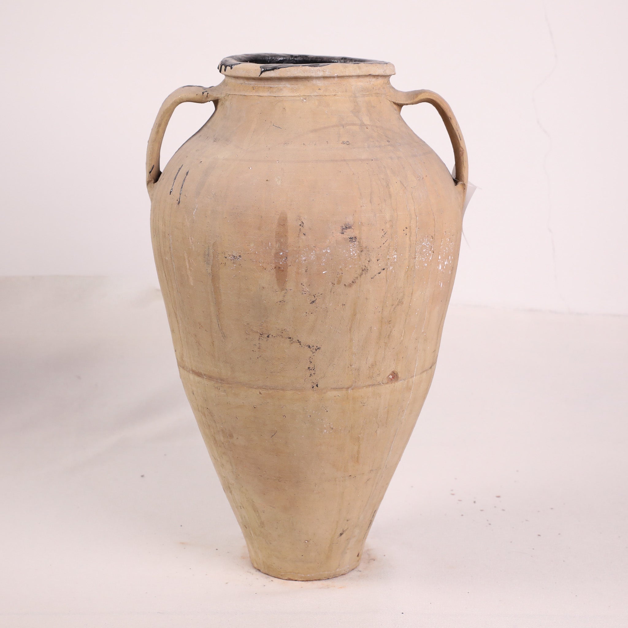 Beige ceramic jar with handles on a white background