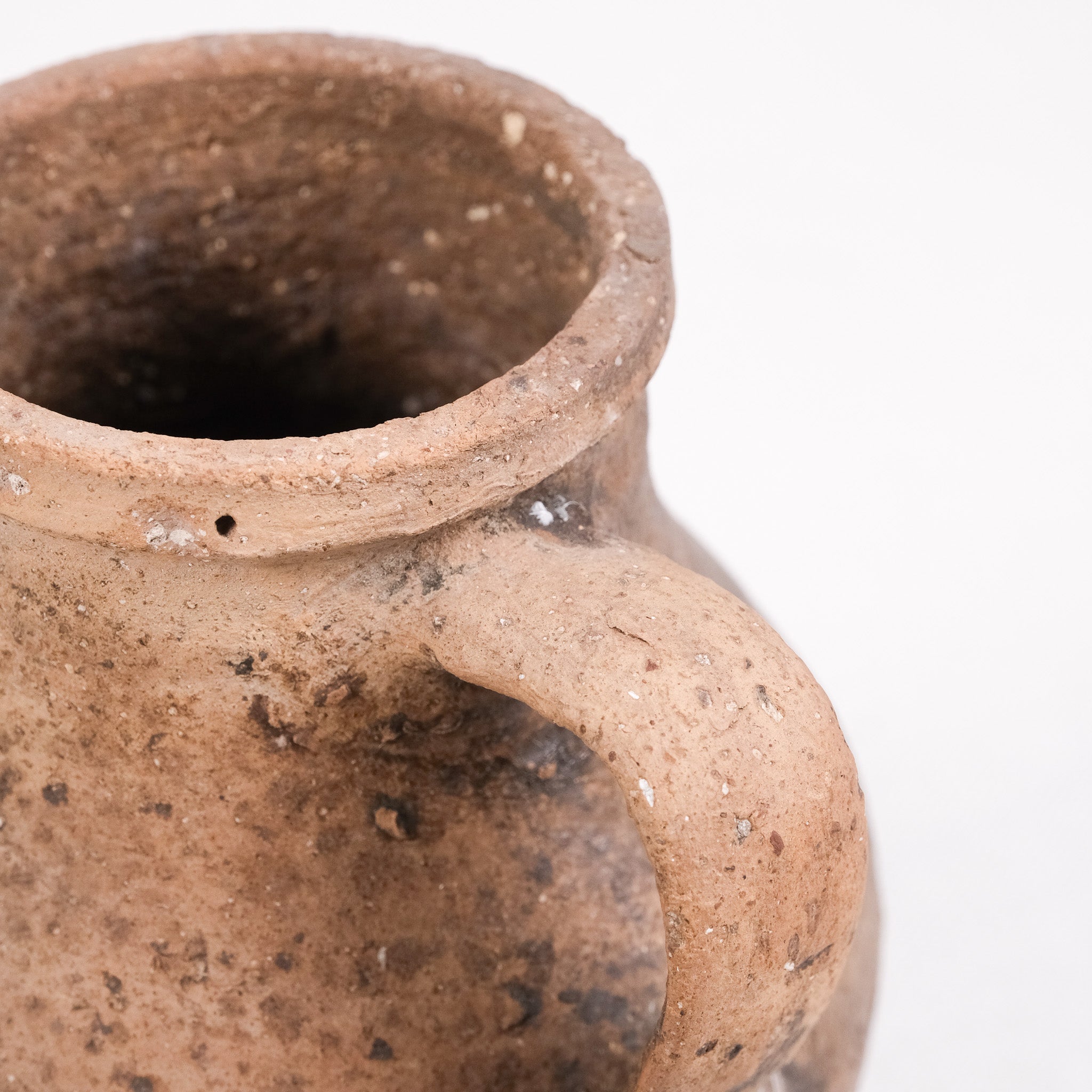 Close-up of a brown ceramic jar with a handle on a white background
