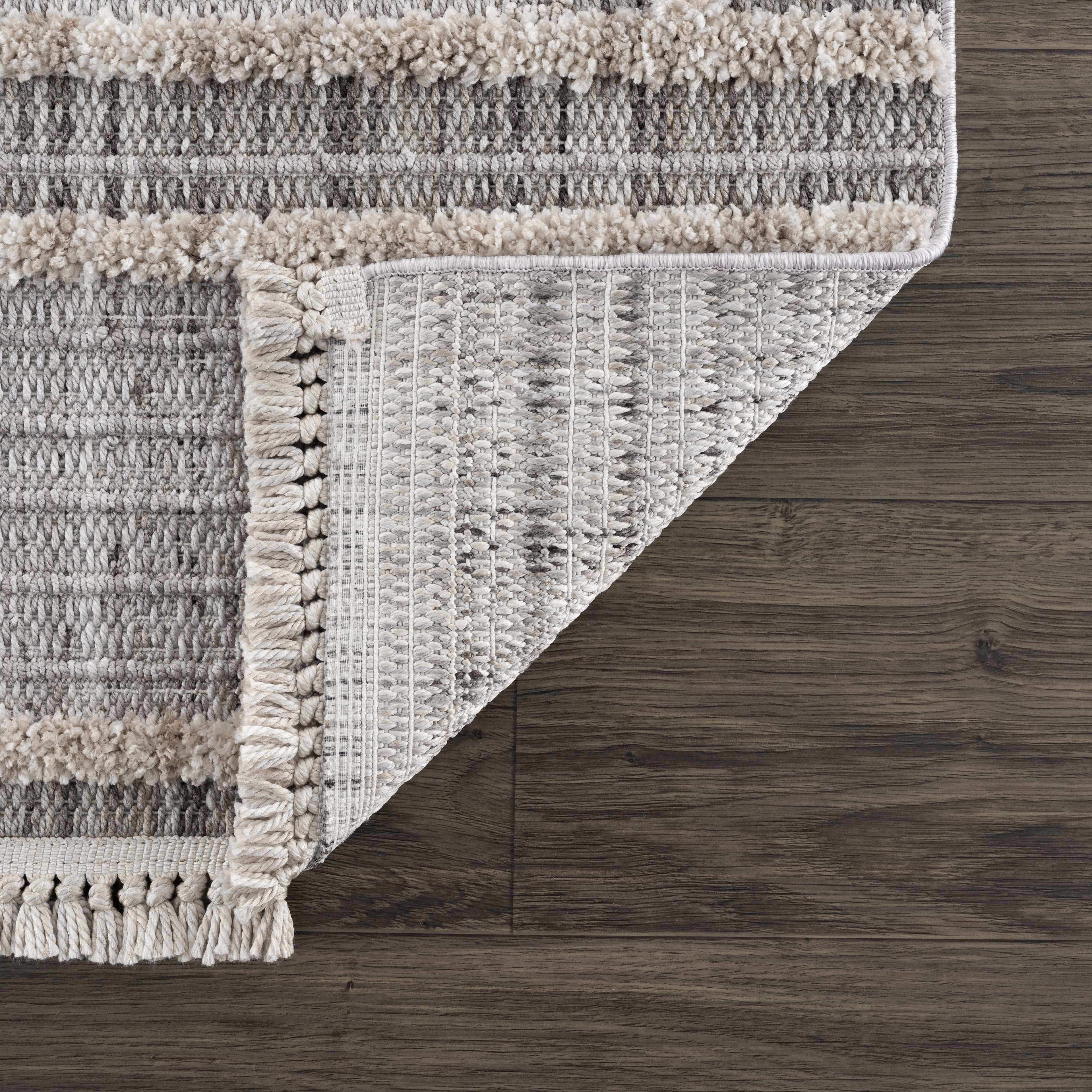 Textured area rug with fringe on a wooden floor