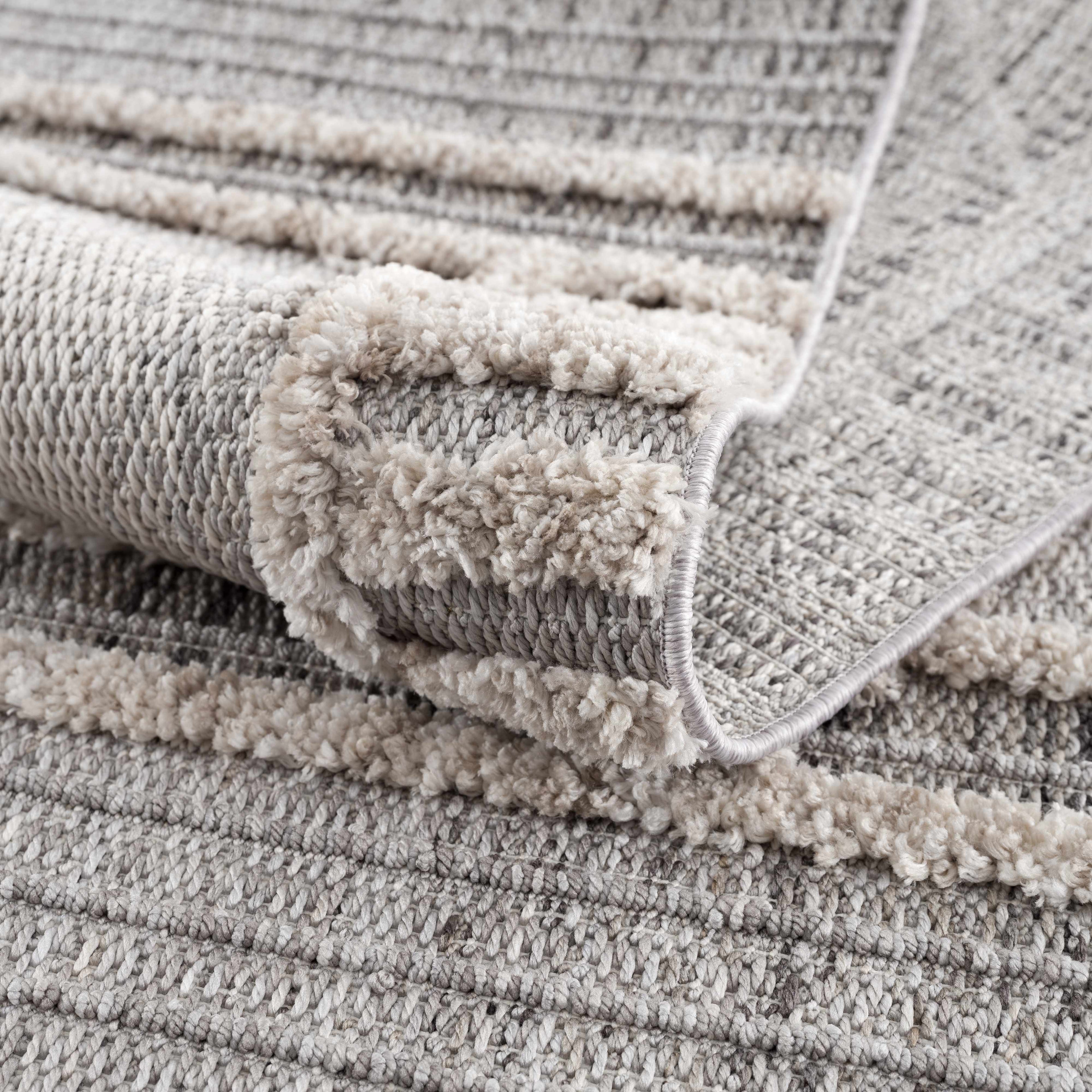 Gray textured rug with a folded corner on a matching background