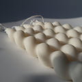 String of white candles on a textured surface with a dark background