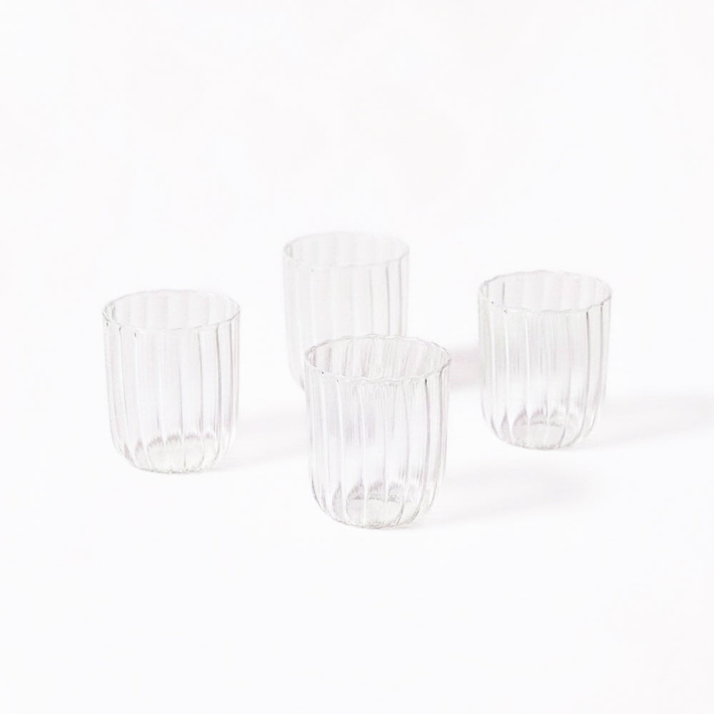 Set of four clear glass tumblers on a white background