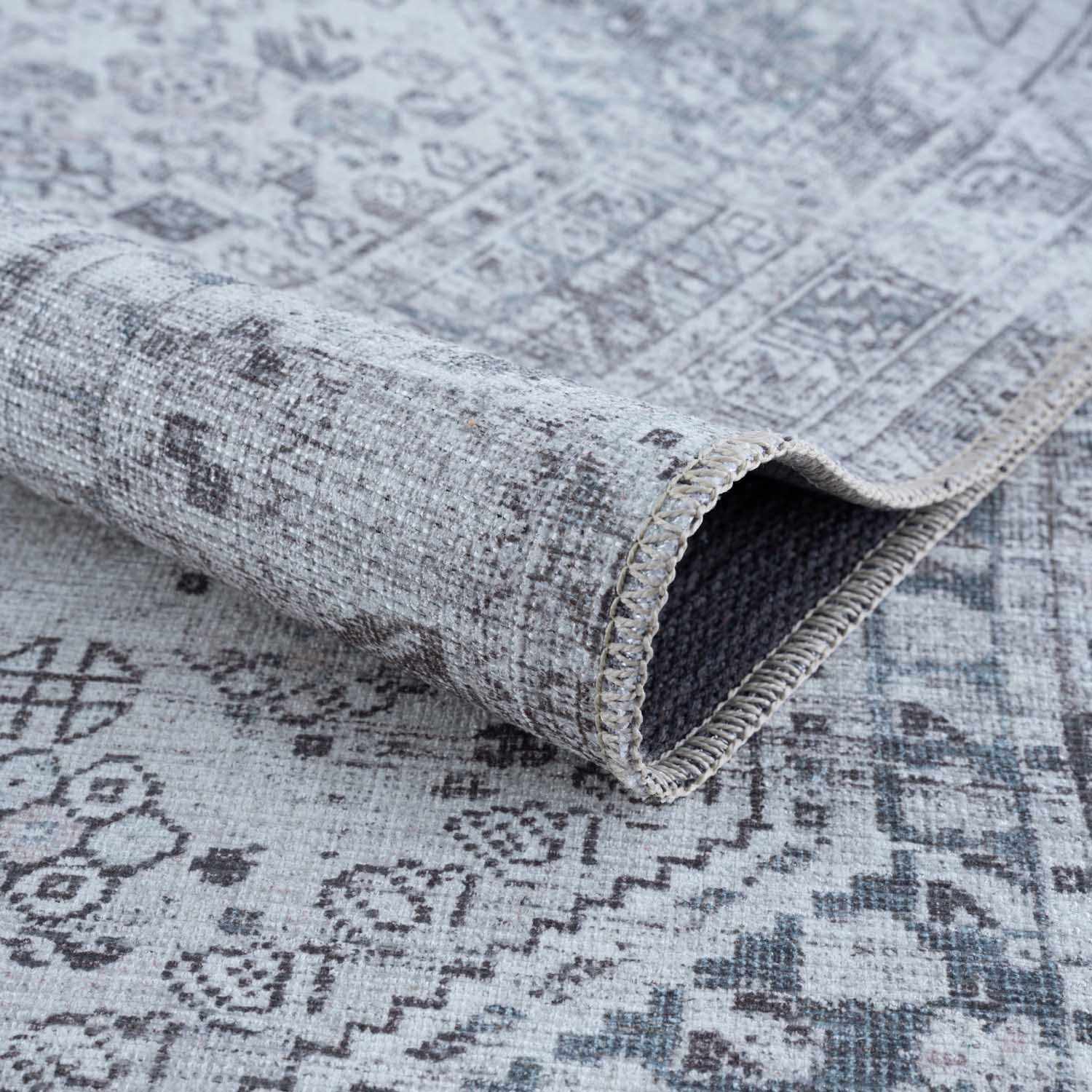 Patterned rug with a rolled-up section on a matching background
