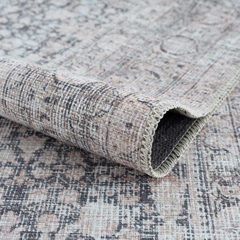 Textured rug with a patterned design, partially rolled up on a matching surface.
