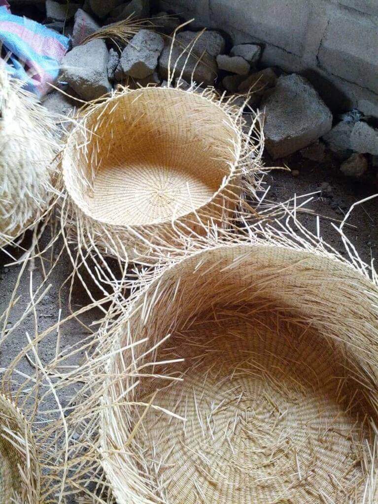 Two woven straw baskets on a stone surface with a concrete wall in the background.