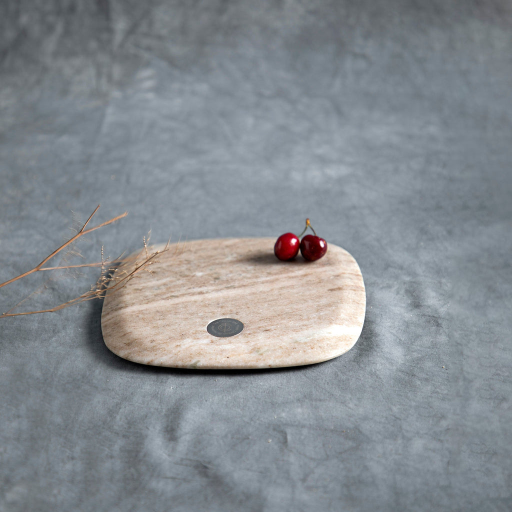 Wooden cutting board with two cherries on a gray surface