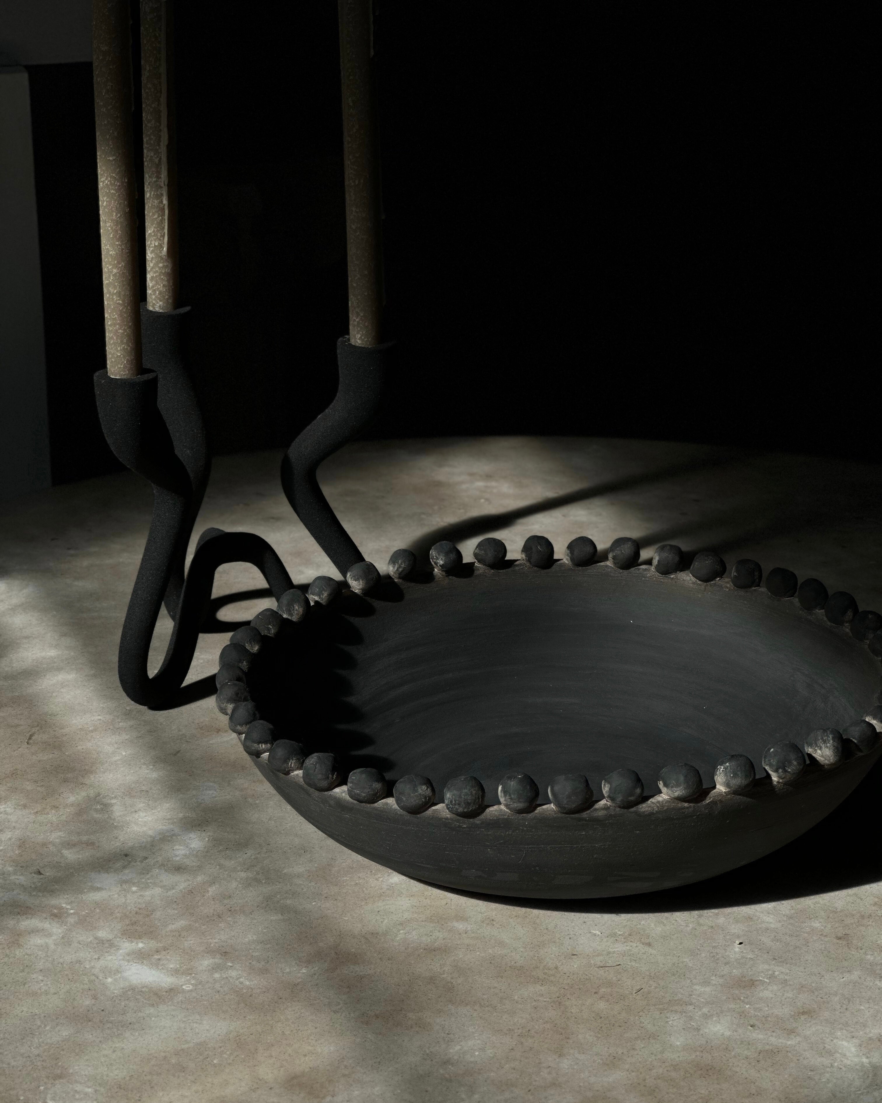 Black metal fire tools including tongs and poker on a stone floor.
