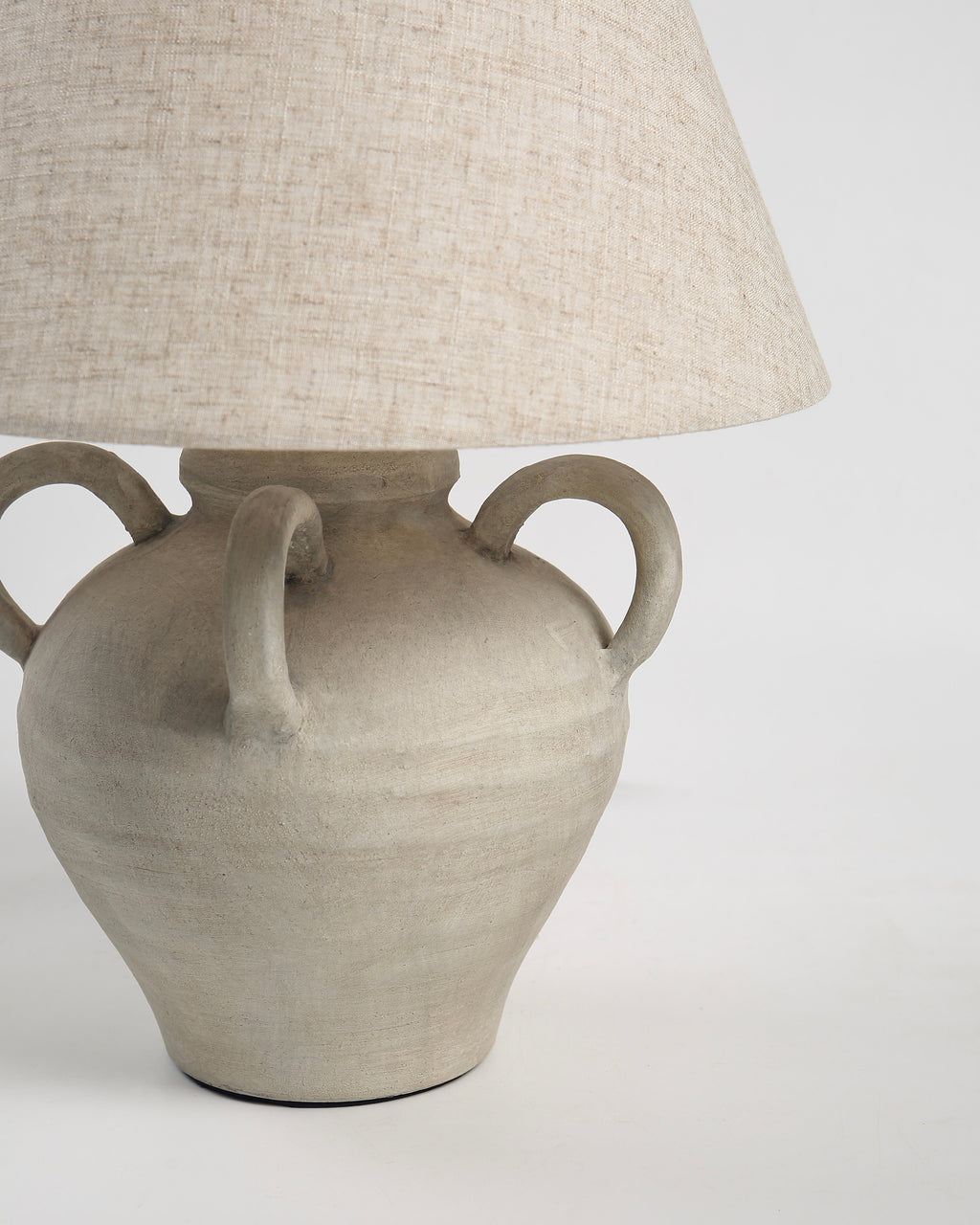 Decorative lamp with a beige ceramic base and a matching lampshade on a white background