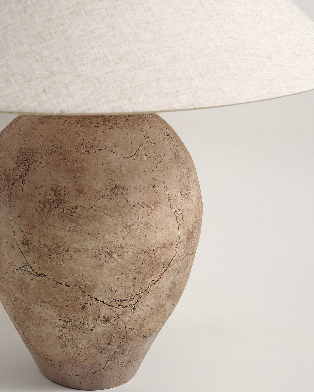 Decorative lamp with a textured base and white lampshade on a light gray background