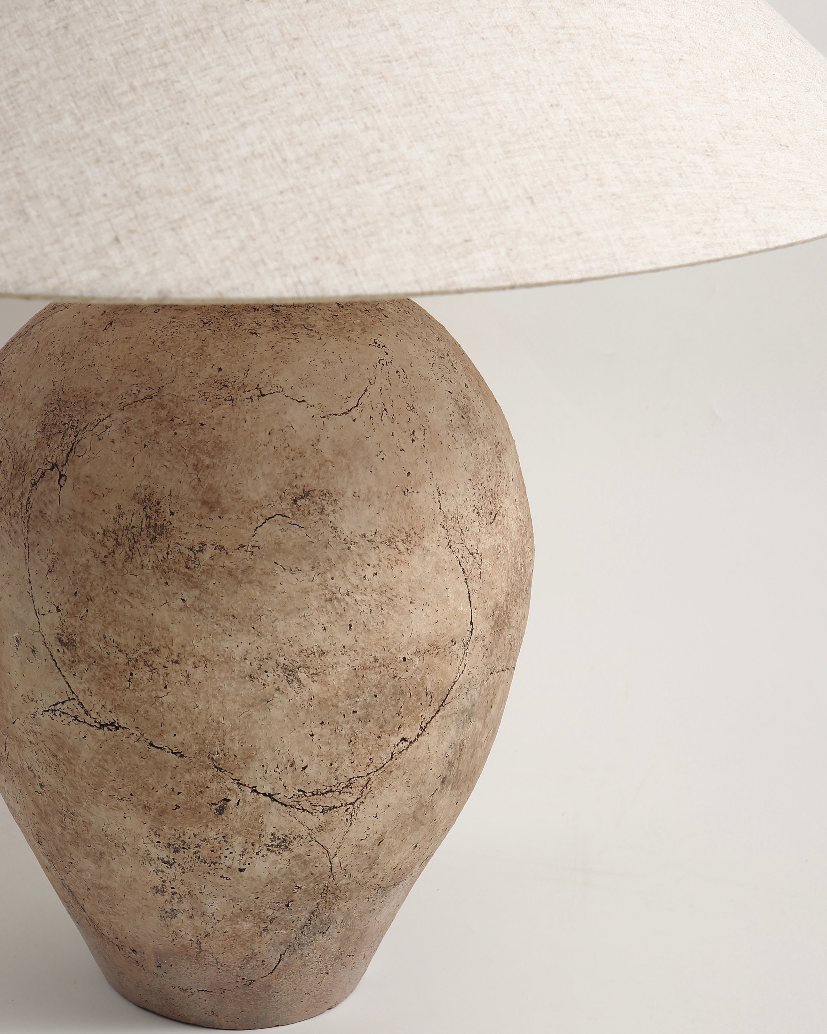 Decorative lamp with a textured base and white lampshade on a light gray background