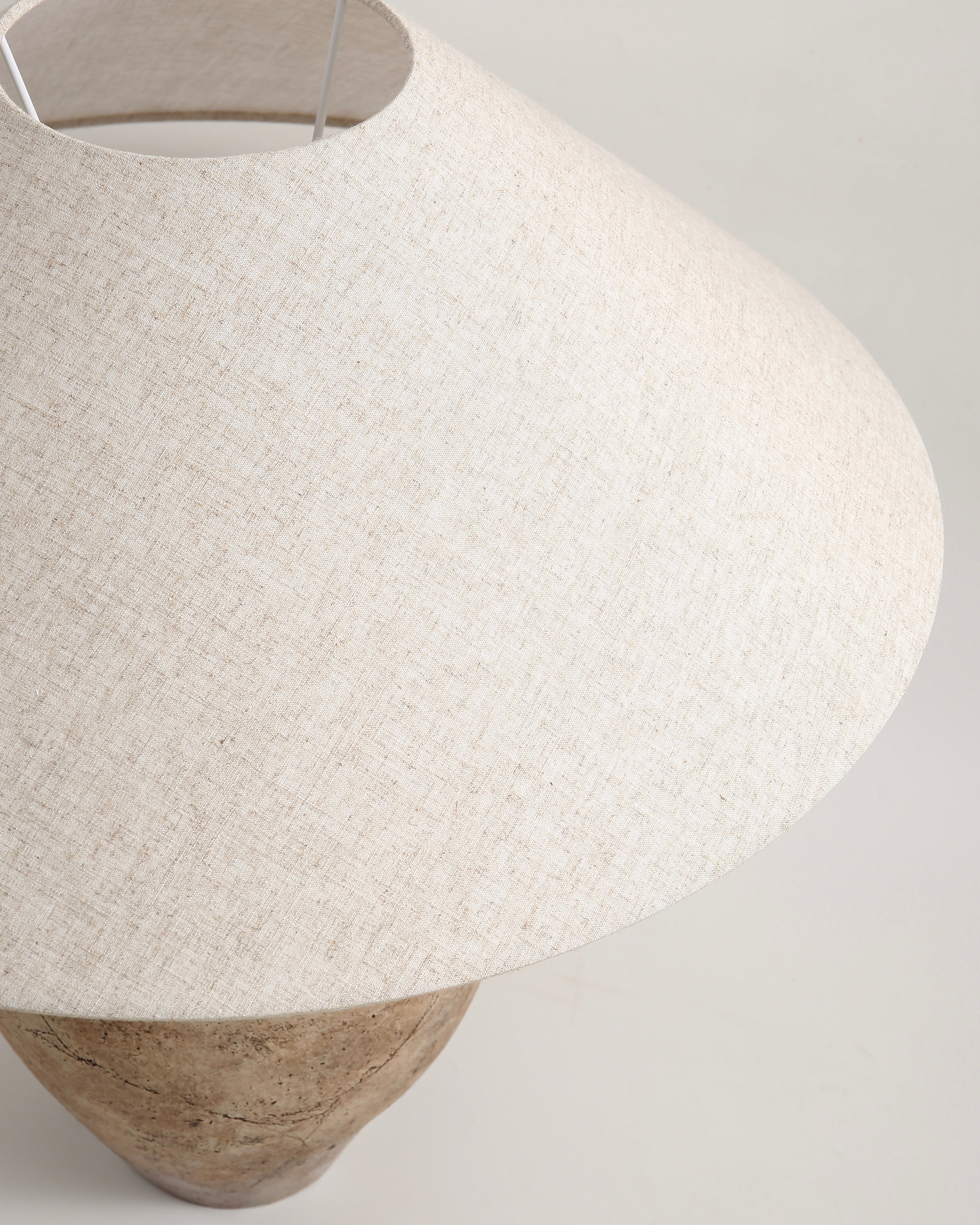 Textured white pendant lamp with wooden base on a light gray background
