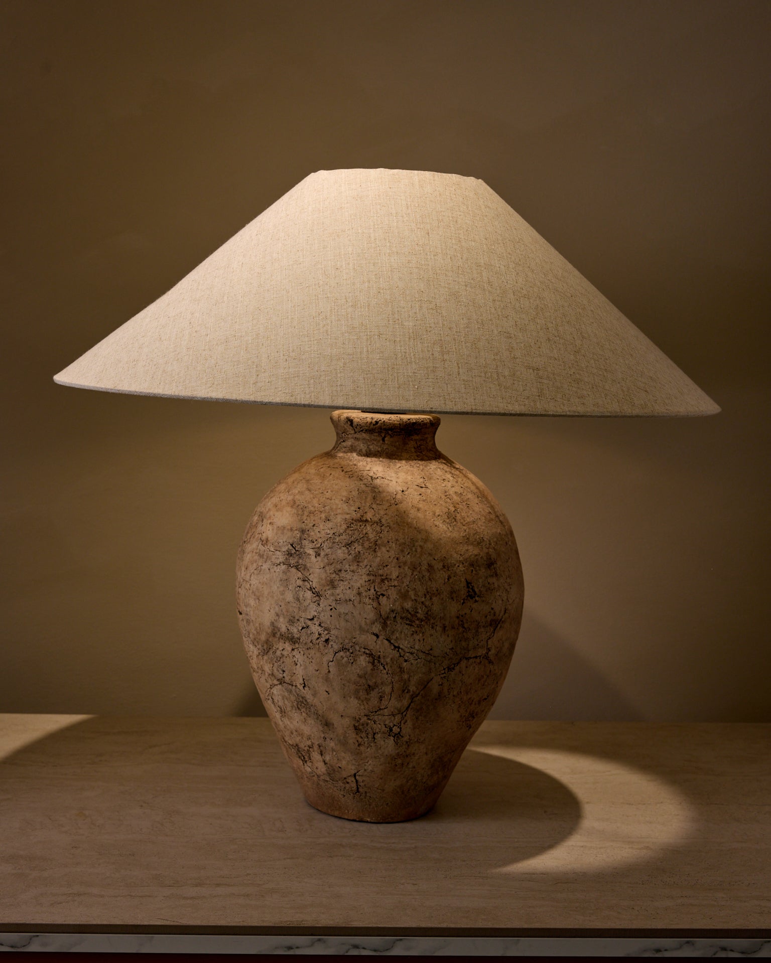 Table lamp with a textured base and linen shade on a neutral background