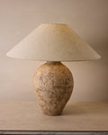 Table lamp with textured base and beige lampshade on a wooden surface.
