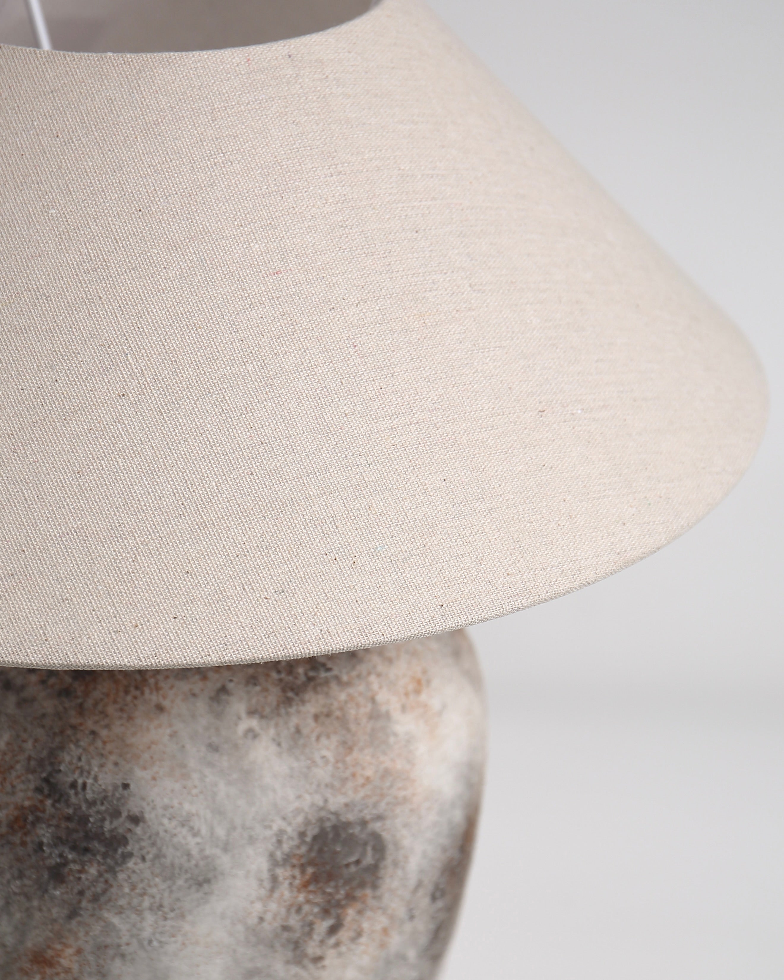 Close-up of a beige lampshade on a textured base against a white background
