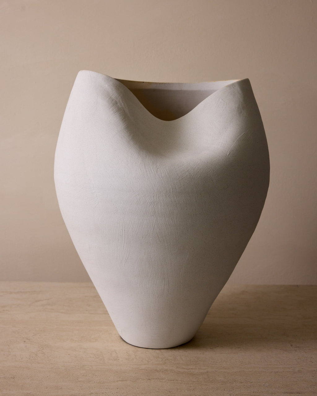 White ceramic vase on a wooden surface with a beige background