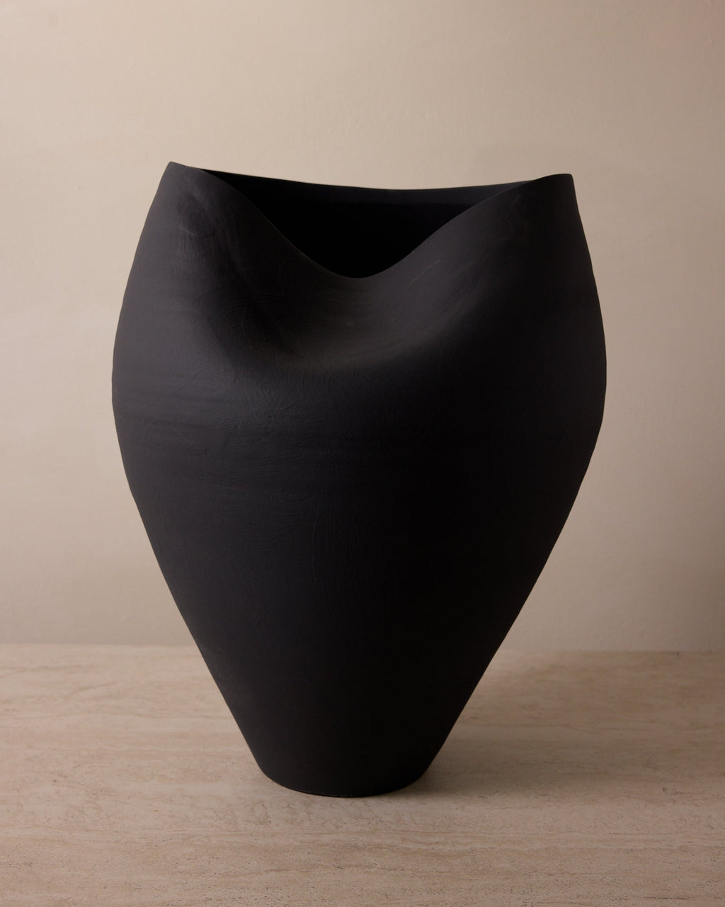 Black vase on a wooden surface with a beige background