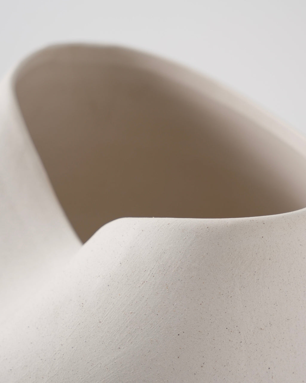 Close-up of a beige ceramic vase with a smooth texture on a light gray background