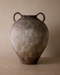 Vintage ceramic jar with handles on a wooden surface and beige background