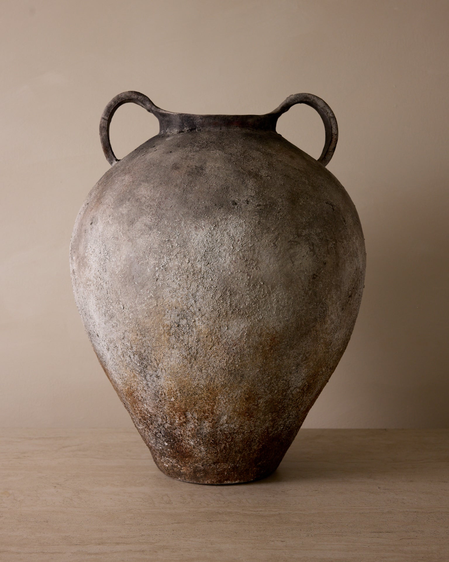 Vintage ceramic jar with handles on a wooden surface and beige background