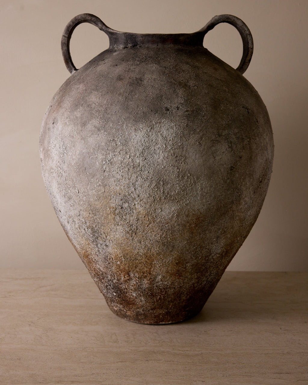Vintage ceramic vase with handles on a wooden surface and beige background