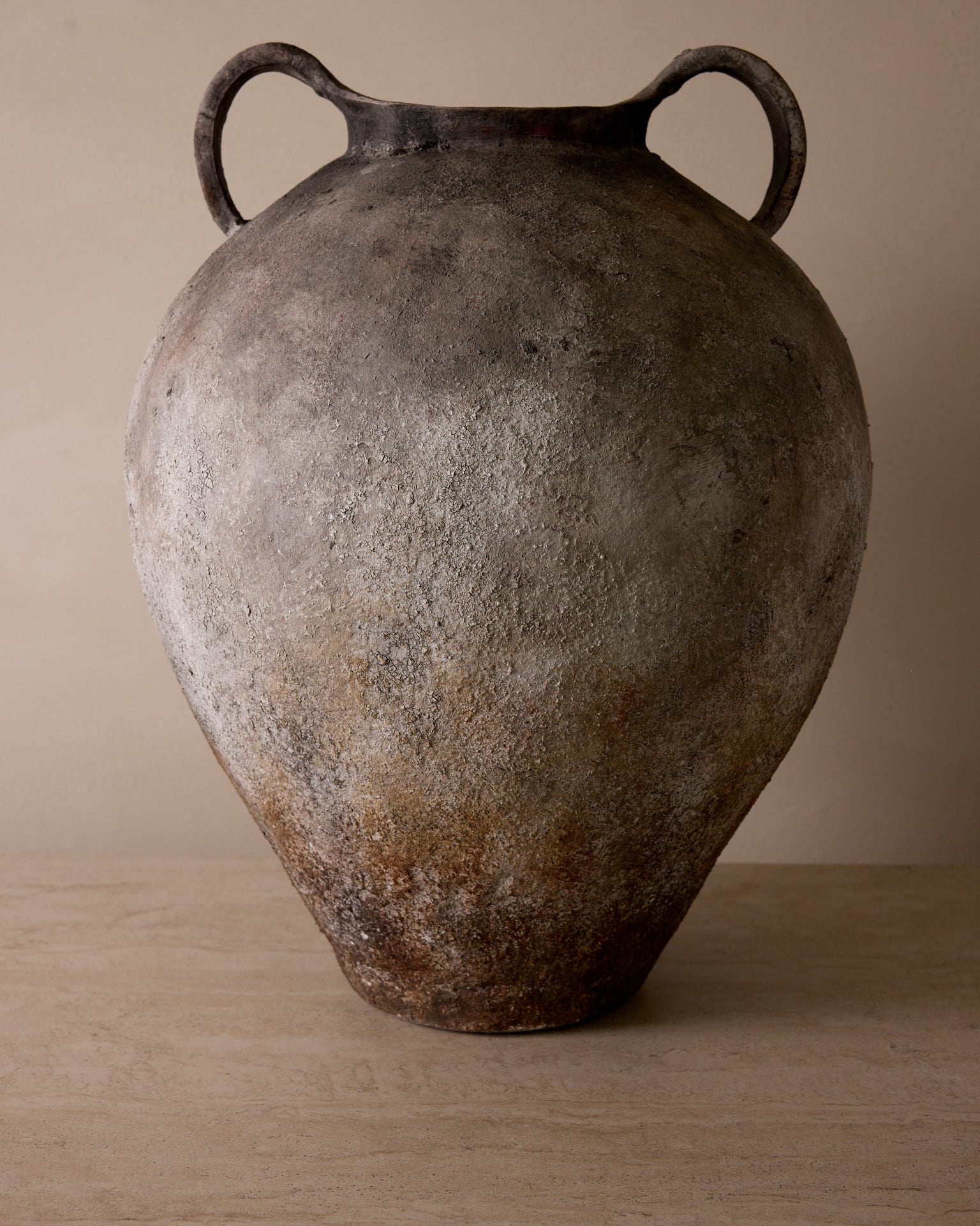 Vintage ceramic vase with handles on a wooden surface and beige background