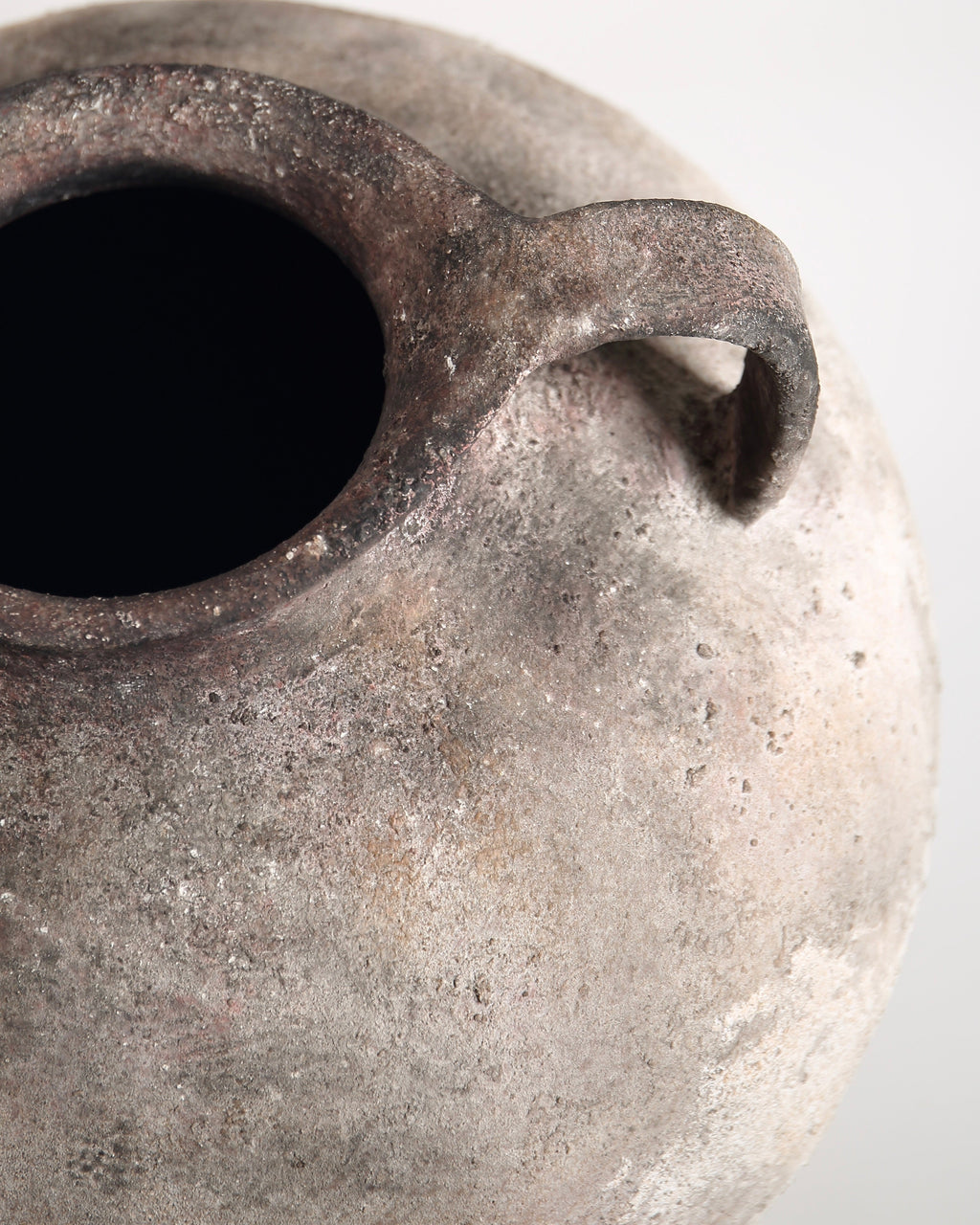 Close-up of a textured ceramic vase with a handle on a white background