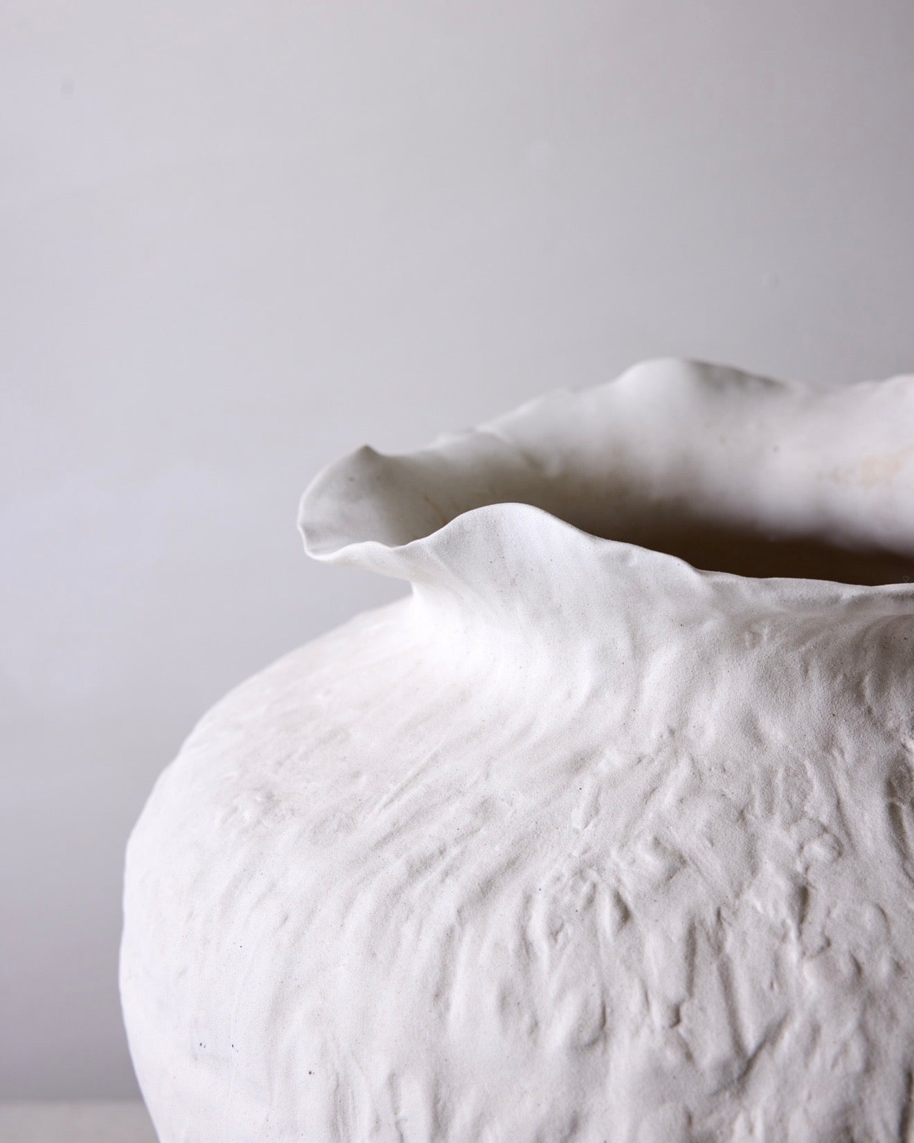 White ceramic vase with textured surface on a light gray background