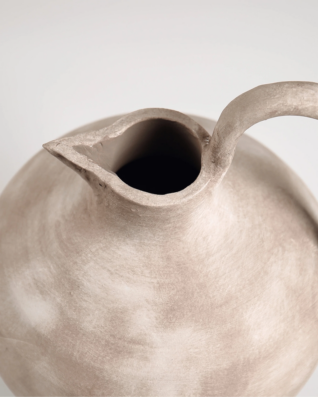 Close-up of a ceramic teapot with a textured surface on a light background